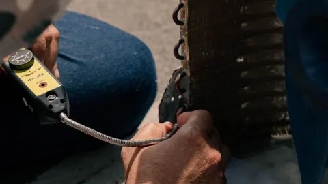 Close-up of hands working to clean AC condenser coils and the metal fins outdoors
