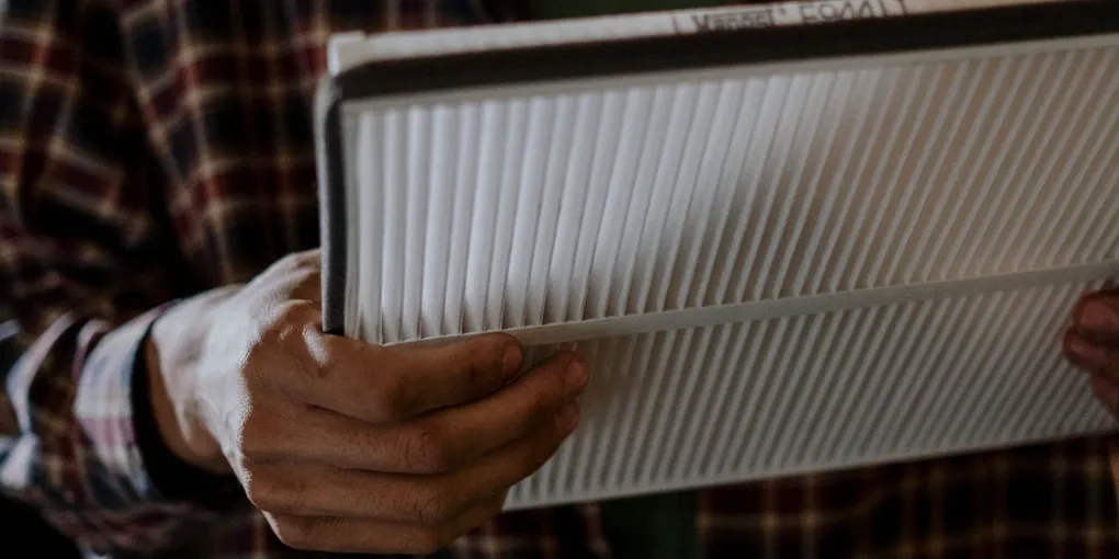 Homeowner holding a pleated HVAC air filter while diagnosing why the house gets so dusty
