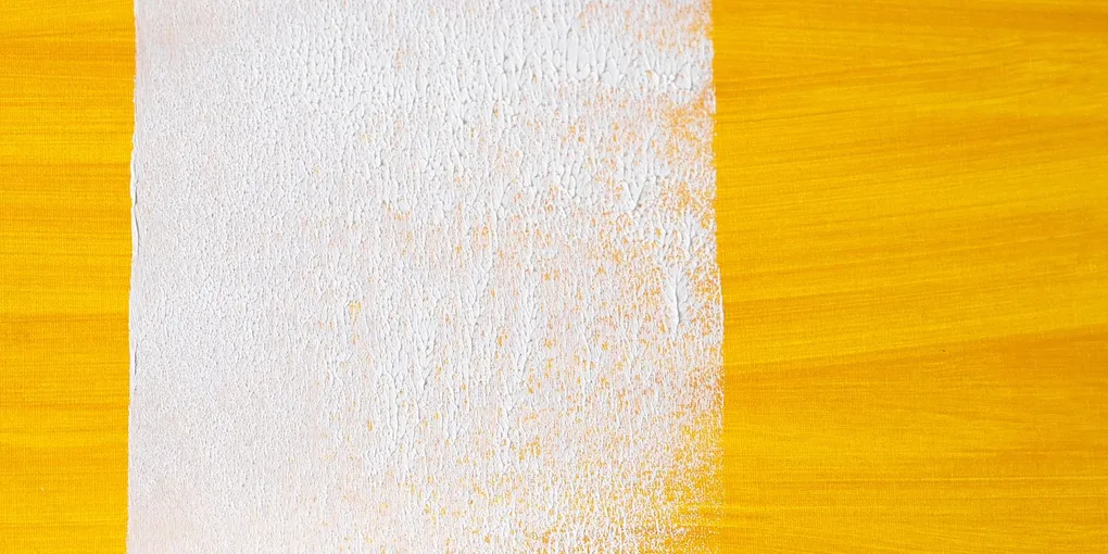 Paint roller laying a white stripe over a dark surface, painting over dark walls