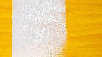 Paint roller laying a white stripe over a dark surface, painting over dark walls