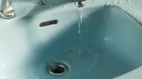 Bathroom sink drain close-up with chrome stopper and fitting, the starting point for running a drain snake