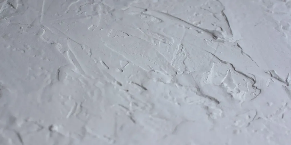 Close-up of troweled knockdown drywall texture on an interior wall under raking light