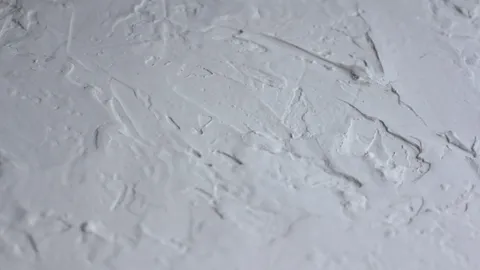 Close-up of troweled knockdown drywall texture on an interior wall under raking light