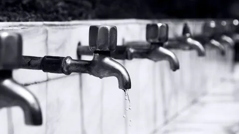 Water dripping from a metal faucet spout in close-up, how to fix a leaky faucet drip