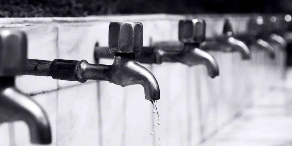 Water dripping from a metal faucet spout in close-up, how to fix a leaky faucet drip