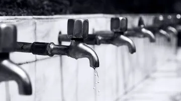 Water dripping from a metal faucet spout in close-up, how to fix a leaky faucet drip
