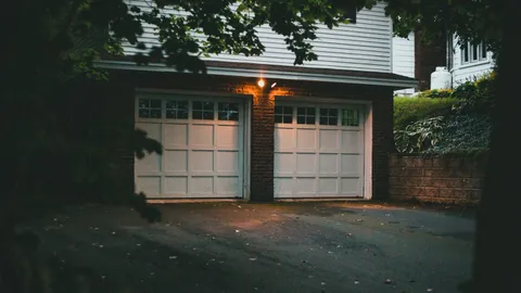 Two white residential garage doors at dusk, fixing garage door sensors that wont close