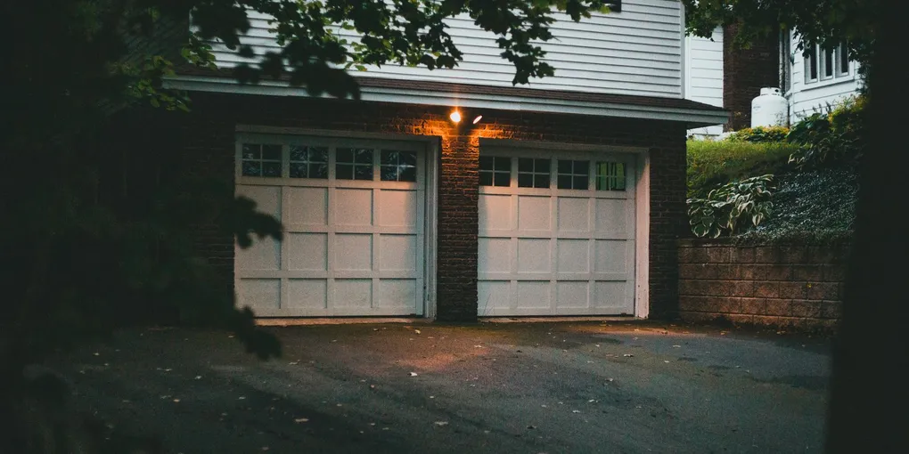 Two white residential garage doors at dusk, fixing garage door sensors that wont close