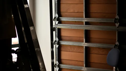 Inside view of vertical metal track and roller brackets on a garage door off track