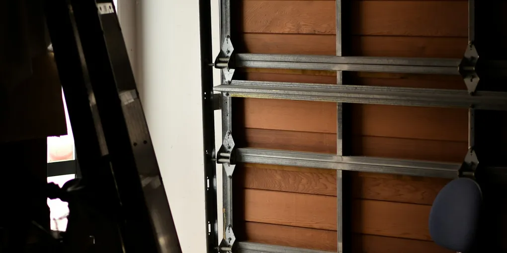 Inside view of vertical metal track and roller brackets on a garage door off track