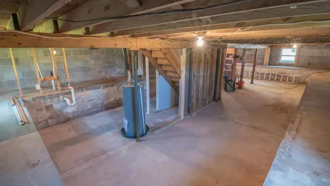 Dim basement corner with concrete walls and damp shadows, why does my house smell musty
