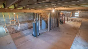 Dim basement corner with concrete walls and damp shadows, why does my house smell musty