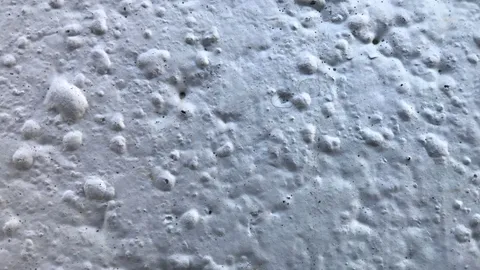 Close-up of a white wall showing raised rounded blisters, bubbles in drywall paint