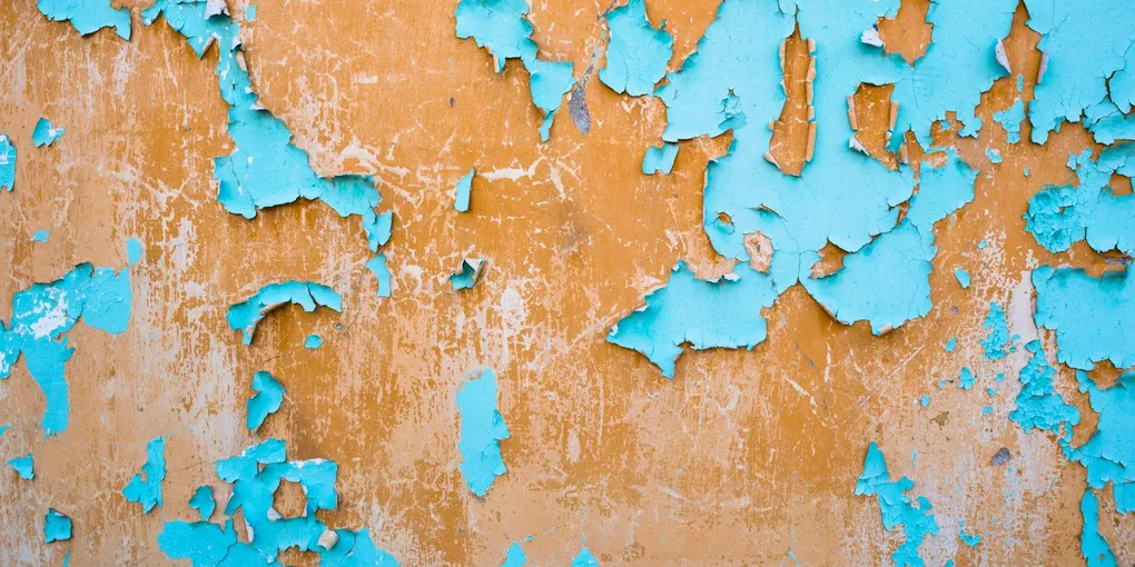Old peeling and cracked paint exposing the wall underneath, fixing paint peeling off a wall