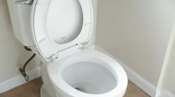 White toilet tank with lid open showing flapper, how to fix a running toilet