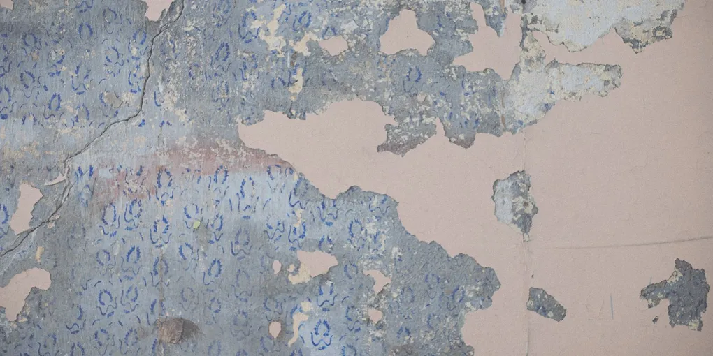 Partially stripped wallpaper hanging off a wall, removing wallpaper without damaging the drywall behind