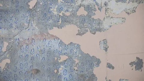 Partially stripped wallpaper hanging off a wall, removing wallpaper without damaging the drywall behind