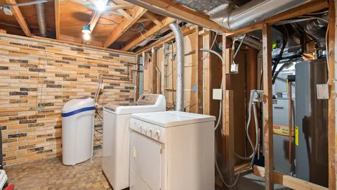 Floor-standing water heater tank in a basement utility area with a leak at the base
