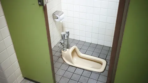 White toilet base with caulk line on bathroom floor, how to fix a wobbly toilet